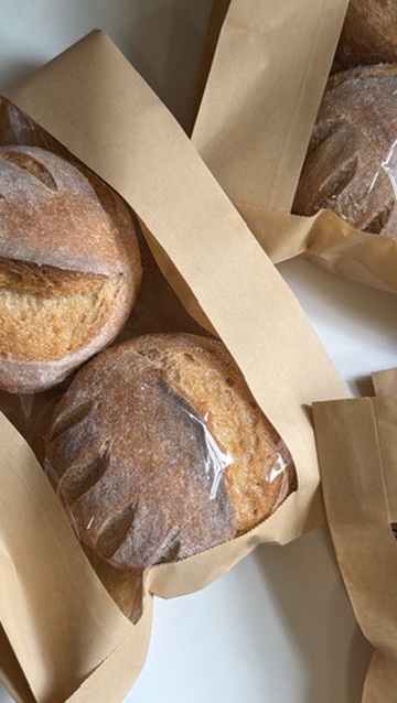Gluten-free sourdough loaves packed in paper bags, ready for pickup